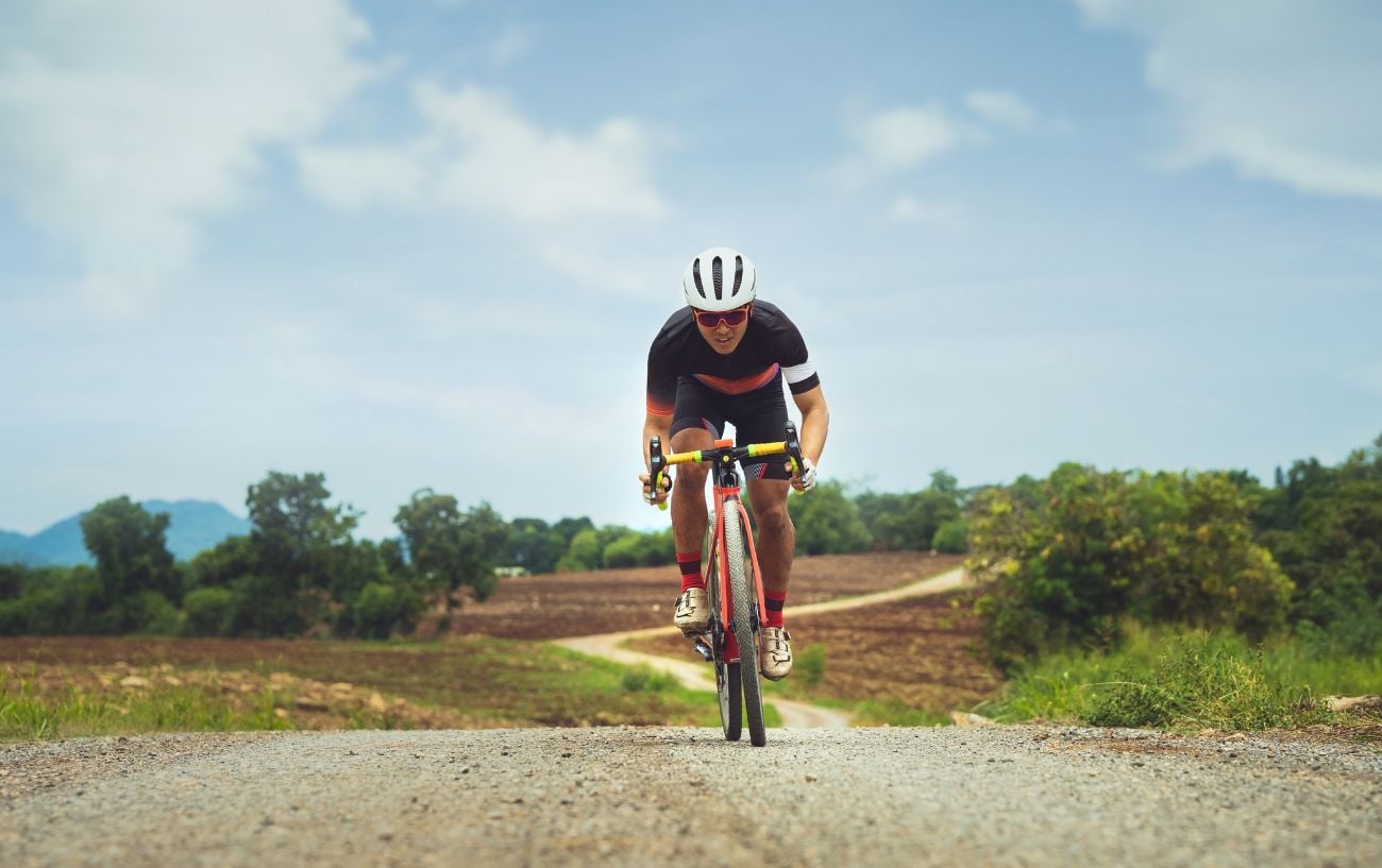 Ultimate Guide To Gravel Wheelsets: Shimano + Campagnolo Edition 2 A gravel cyclist climbs a dirt hill on an orange bike.